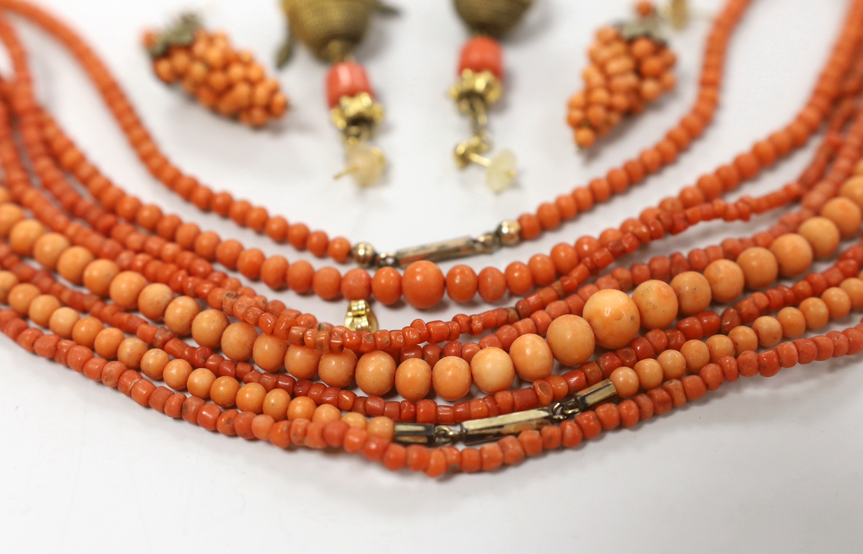 Three coral bead necklaces, largest 110cm and two pairs of earrings including coral cluster modelled as a bunch of grapes.